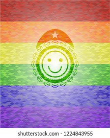 happy face icon inside emblem on mosaic background with the colors of the LGBT flag