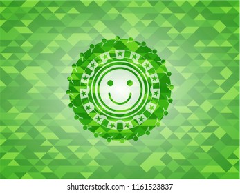 happy face icon inside green emblem with triangle mosaic background