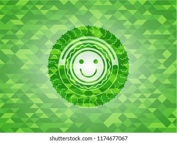 happy face icon inside green emblem with triangle mosaic background