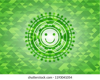 happy face icon inside green emblem with triangle mosaic background