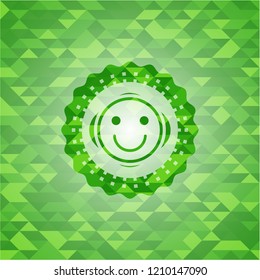 happy face icon inside green emblem with mosaic background
