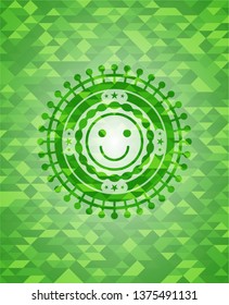 happy face icon inside green emblem. Mosaic background