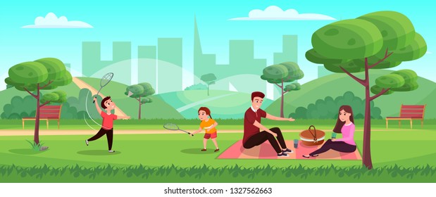 Happy family with children in the park, children play badminton. Parents sit on the grass. Panoramic banner - urban landscape. Summer time for walking and having fun outside.