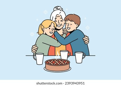 Happy family of grandmother and two little grandchildren hugging sitting at table with hot cake and mugs of tea. Smiling grandmother rejoices at meeting great-grandchildren after long absence