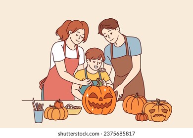 Happy family makes halloween pumpkins to decorate house for october 31st and celebrate all saints day. Boy together with parents, dressed in aprons, cuts out jack-o-lanterns for celebration halloween