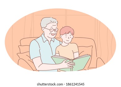 Happy family, parenthood, children concept. Happy grandfather sitting and reading book together with smiling grandson at home. Togetherness, happiness, grandparent, leisure, activity 