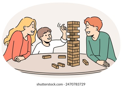 Happy family plays jenga with child enjoying board game and developing fine motor skills in baby. Satisfied boy plays jenga with parents pulling wooden block out of unstable tower.