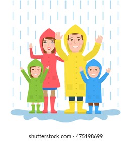 happy family in raincoats standing under the rain