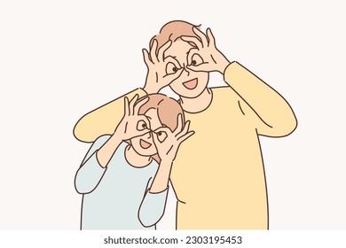 Happy father and daughter make funny faces to have fun putting fingers to eyes instead of glasses. Happy family of man and teenage girl having rest together posing with funny grimace