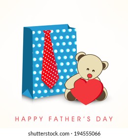 Happy Father's Day celebrations concept with shopping bag, necktie and teddy bear holding red heart shape on grey background.