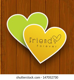 Happy friendship day concept with paper sticky in heart shape on wooden background.