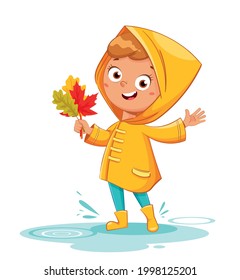 Happy funny child in yellow raincoat and rubber boots holding leaves, rainy autumn