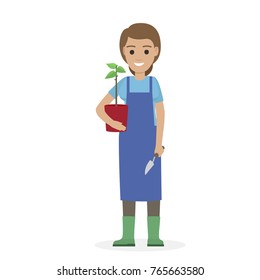 Happy gardener in blue apron and verdant gumboots holds green plant in red pot in one hand and garden shovel in other vector illustration.