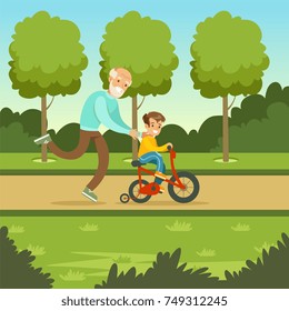 Happy grandfather teaching kid boy to ride the bicycle