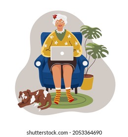 Happy grandmother with the laptop computer at home. Old woman online working and the dog sleeps at her feet