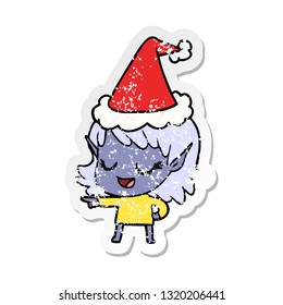 happy hand drawn distressed sticker cartoon of a elf girl pointing wearing santa hat
