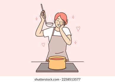 Happy housewife woman cooks soup standing at stove with saucepan and tastes after adding spices. Positive housewife in apron preparing dinner waiting for arrival of boyfriend or husband