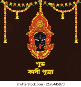 Happy Kali Puja Font Written In Bengali Language With Hindu Mythology Goddess Kali Maa Face And Floral Garland (Toran) On Brown Mandala Background.