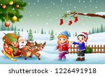 Happy kids and santa claus with elf riding on a sleigh with bag of gifts pulled by reindeer