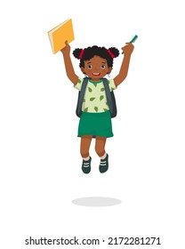 Happy little African girl student jumping holding backpack and book feeling excited to be back to school