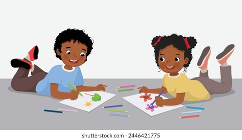 Happy little African kids drawing painting together lying on the floor
