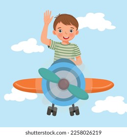 happy little boy flying an airplane waving hand in the blue sky