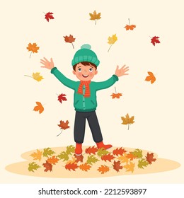 happy little boy playing outside with fallen leaves in autumn