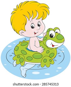 Happy little boy smiling and swimming with a rubber ring