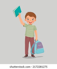 Happy little boy student with backpack holding backpack and book feeling excited to be back to school