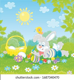 Happy little bunny painting and decorating Easter eggs with bright and colorful paints and a paintbrush on green grass of a pretty forest glade on a sunny spring day, vector cartoon illustration