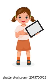 Happy little girl holding digital tablet with finger pointing to empty screen or copy space for texts, messages and advertising content. Kids and electronic gadget devices concept for children.

