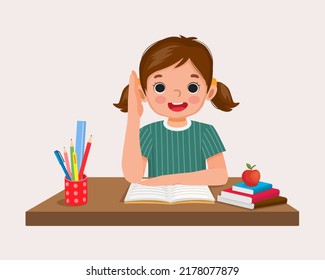 happy little girl student rising hand asking question sitting at her desk in the classroom