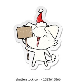happy little hand drawn distressed sticker cartoon of a dog holding sign wearing santa hat