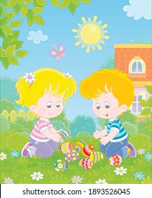 Happy little kids collecting colorfully painted eggs after an Easter egg hunt on green grass of a spring lawn, among bushes and trees in a garden of their house, vector cartoon illustration