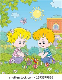 Happy little kids collecting colorfully painted eggs after an Easter egg hunt on green grass of a spring lawn, among bushes and trees in a garden of their house, vector cartoon illustration