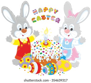 Happy little rabbits with a decorated Easter cake and colorfully painted eggs
