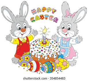 Happy little rabbits with a decorated Easter cake and colorfully painted eggs