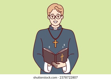 Happy man priest with bible and golden cross on neck smiles preaching and reading prayers in christian church. Young priestly mentor monastery or catholic cathedral teaches religious texts