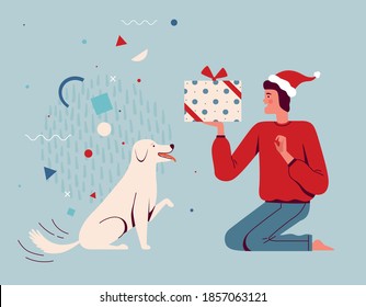 Happy man in santa hat gives a present for Christmas to his dog. Raising and training a puppy. Pet party