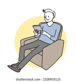 Happy man sitting comfortable and using tablet. Young man reclining on armchair and using digital tablet. Smiling man using tablet for watching movie on couch. Handsome man using digital tablet.