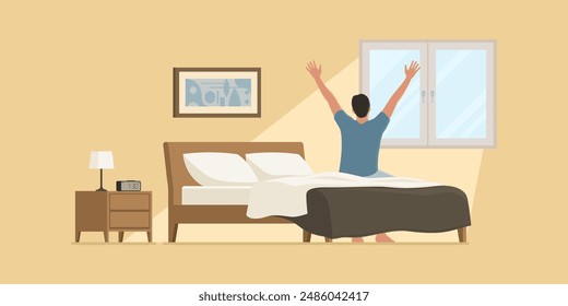 Happy man waking up early in the morning, he is sitting on the bed and stretching his arms while looking outside the window