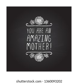 Happy mothers day handlettering element with flowers on chalkboard background. You are an amazing mother. Suitable for print and web