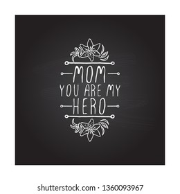 Happy mothers day handlettering element with flowers on chalkboard background. Mom you are my hero. Suitable for print and web