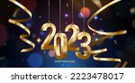 Happy New Year 2023. Hanging golden 3D numbers with ribbons and confetti on a defocused colorful, bokeh background.