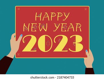 Happy New Year 2023.  Two hands with blue manicure holding a bright poster with an inscription. Author's font - yellow letters and numbers with a geometric decor on a red background. Retro 60s