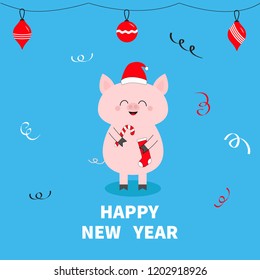 Happy New Year. Christmas ball toys. Pig holding candy cane, sock. Red Santa Claus hat. Cute funny cartoon character. Flat design. Blue winter background with confetti. Vector illustration