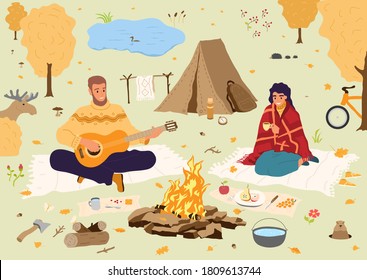 Happy people at autumn vacation.Man and woman sitting at camp-fire in forest. Picnic of tourists in fall wood on countryside. Traveling couple in weekend activity.