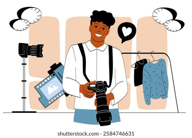 Happy photographer holding a camera in a stylish studio with film rolls, clothing rack, and equipment, representing creativity and fashion photography