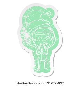 happy quirky cartoon distressed sticker of a astronaut wearing santa hat