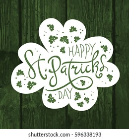 Happy Saint Patrick's Day logotype. Celebration design for March, 17th. Hand drawn lettering typography. On green wooden background